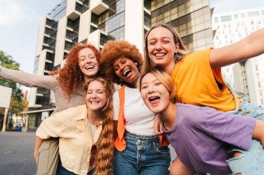 Gülümseyen ve birlikte eğlenen tek kadın grubunun portresi. Heyecanlı kadınlar kameraya dostça bir ifadeyle bakıyor. Sosyal bir toplantıda pozitif ve kaygısız kızlar. Çok ırklı, neşeli hanımlar.