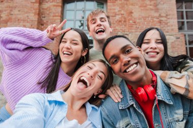 Bir grup çok ırklı yetişkin öğrenci gülümseyip selfie çekiyorlar. Mutlu uluslararası gençlerin gülen portresi. Neşeli arkadaşlar eğleniyor. Dostça bir buluşmada sınıf arkadaşları