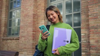 Genç Asyalı liseli kız cep telefonuyla gülümsüyor. Üniversite kampüsündeki akıllı telefon uygulaması ile internette gezinen Çinli genç bir kız. Taylandlı sınıf arkadaşım cep telefonunu izliyor.
