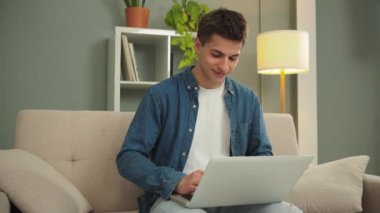 Gündüz vakti evde dizüstü bilgisayarla çalışan mutlu bir serbest çalışan. Oturma odasında bilgisayarla gülümseyen ve internette gezinen genç bir adam. Girişimci banka finansmanı ve yatırımları arıyor