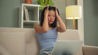 Burnout, anksiyete problemleri olan serbest çalışan bir kadın evde oturuyor. Genç Asyalı kadın dizüstü bilgisayar kullanmaktan yorulmuş, stres ve baş ağrısı çekiyor. Üzgün ve mutsuz öğrenci kız yorgun.