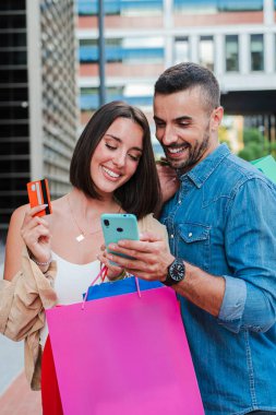 Dikey. Genç müşteriler kredi kartıyla pazar yeri başvurusunda bulunuyorlar. Alışveriş merkezinde satış yapmak için internetten cep telefonu alan bir çift. İndirim aramak için telefon kullanan insanlar.