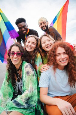 Dikey. Bir grup genç LGBT gülerek eşcinsellerin gurur gününü gökkuşağı bayrağıyla kutluyor. Çeşitli arkadaşlar kameraya bakıyor ve haklar yürüyüşünde eğleniyorlar. Eşitlik ve özgürlük. Yüksek