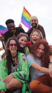 Dikey. Bir grup genç LGBT gülerek eşcinsellerin gurur gününü gökkuşağı bayrağıyla kutluyor. Çeşitli arkadaşlar kameraya bakıyor ve haklar yürüyüşünde eğleniyorlar. Eşitlik ve özgürlük. Yüksek