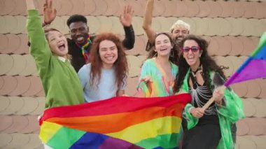 Bir grup genç LGBT gülerek eşcinsellerin gurur gününü gökkuşağı bayrağıyla kutluyor. Çeşitli arkadaşlar kameraya bakıyor ve haklar yürüyüşünde eğleniyorlar. Eşitlik ve cinsellik özgürlüğü. Yüksek