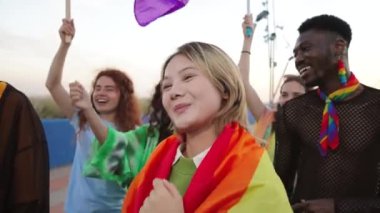 Eşcinsel onur gününü gökkuşağı bayrağıyla kutlayan bir grup LGBT çükünün yakın portresi. Genç yetişkin LGTB arkadaşları cinsel haklar partisinde özgürlük ve cesaret ifadesiyle gülümsüyor
