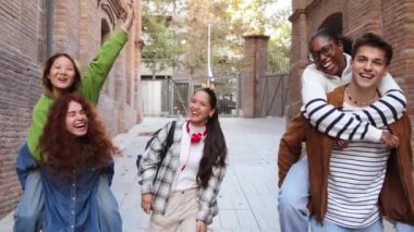 Bir grup erkek öğrenci, kız arkadaşlarına sırtına biniyor, yürüyor ya da sınıfa koşuyor. Heyecanlı çok ırklı sınıf arkadaşları üniversite kampüsünde birlikte eğleniyorlar. Okula dönelim. Yüksek