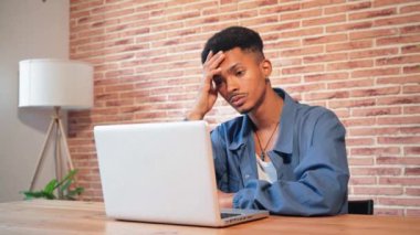 Evde dizüstü bilgisayarla çalışan yorgun ve stresli bir Afrikalı Amerikalı adam baş ağrısı ve zihinsel yorgunluktan muzdarip. Yetişkin bir erkek, mali durumu ya da iş sorunu hakkında endişeli görünüyor. Yüksek