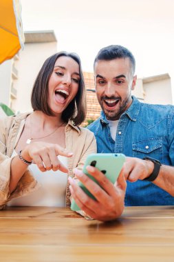 İnternetten alışveriş yapan genç bir çift, cep telefonu uygulaması kullanarak satış bulduklarına seviniyorlar. Mele ve kadın bir cep telefonuyla medyayı paylaşırken eğleniyorlar. Akıllı telefon uygulamasını izleyen heyecanlı arkadaşlar. Yüksek