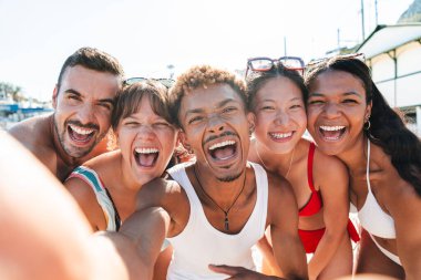 Çok ırklı bir arkadaş grubu sahilde yaz tatilinin tadını çıkarırken bir akıllı telefonla selfie çekiyor. Genç turistler bir fotoğrafta gülen yüzlerini yakalıyorlar. Yüksek