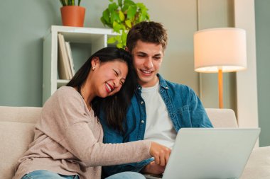 Evdeki kanepede oturan çok ırklı genç çift, bir dizüstü bilgisayarla otel odasını arayıp, rezervasyon yaptırıyor ve tatilleri için uçak bileti alıyorlar. Erkek arkadaş ve kız arkadaş internette bilgisayarla geziniyor.