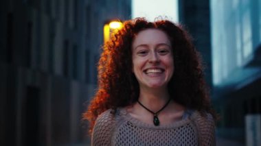 Kameraya bakan genç bir kadının yakın plan portresi. Kız arkadaş canlısı bir ifade takınıyor, mutlu bir şekilde gülümsüyor ve iyimserlik yayıyor. Kadın kıyafetleri ona olumlu bir hava katıyor. Yüksek kalite 4k