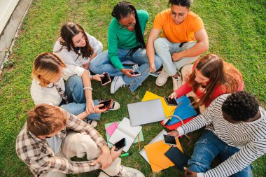 Üniversite kampüsünün bahçesinde bir grup öğrencinin yüksek açılı görüntüsü ya da havası. Sınıf arkadaşları lisenin dışında dinleniyor, birlikte konuşuyorlar. Akıllı telefonlar kullanan gençler.