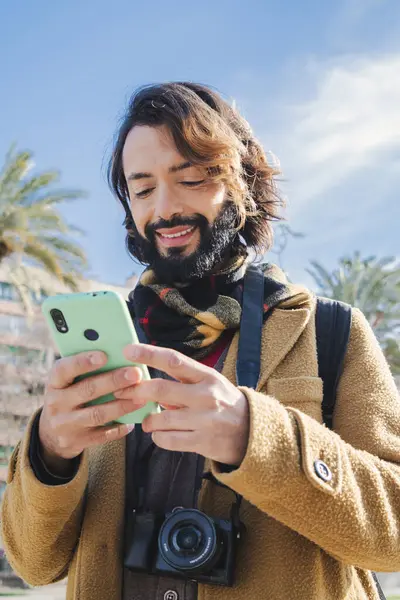 Dikey Mutlu Sakallı Adam internette gezinmek için cep telefonu uygulaması kullanıyor. Turist gülümsüyor ve açık havada duran akıllı bir telefon haritasıyla yer arıyor. Cep telefonu tutan bir erkek. Yüksek