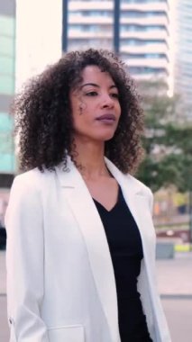 Ciddi bir ifadeyle modern işyerinde kararlı bir şekilde yürüyen Afrikalı Amerikalı bir iş kadınının ağır çekim dikey görüntüsü. Şık, profesyonel bir kadın. Başarılı çalışan bayan, iş adamı.