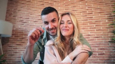 Beyaz bir çift yeni evlerinin ya da evlerinin anahtarını gururla gösteriyorlar. Konut kredisini tamamladıktan sonra ev sahibi ya da kiracı olmaktan memnuniyet duyarlar. Ev sahipliği.