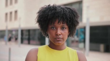 Dışarıda kameraya bakan Afro-Amerikan bir kızın portresini yakından çek. Düşünceli genç bir yetişkin kadın önüne bakıyor. Gururlu afro kadın düşünceli bir ifadeyle bakıyor.