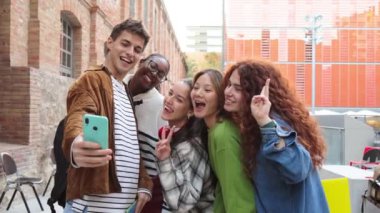 Genç bir öğrenci havalı arkadaşlarıyla akıllı telefon kullanarak selfie çekiyor. Bir grup çok ırklı sınıf arkadaşı arkadaşça bir toplantıda üniversite kampüsünde cep telefonuyla fotoğraf çekiyorlar. Yüksek