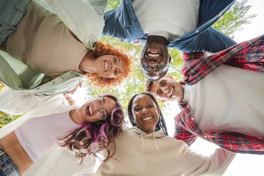 Bir grup çok ırklı mutlu gencin birbirine daire şeklinde sarıldığı, gülümseyen yüzlerle kameraya bakan, arkadaşlığı, çeşitliliği ve dışarıdaki birlikteliği temsil eden,