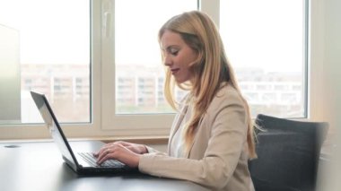 Ofis masasında dizüstü bilgisayarla çalışan bir iş kadını. Takım elbiseli başarılı bir yönetici iş kadını borsayı analiz etmek için bilgisayar kullanıyor. Beyaz yakalı kadın işçi iş e-postası gönderiyor.