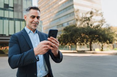 Uzayı kopyala Akıllı telefon kullanan iş adamı, cep telefonu uygulamasına odaklanan, profesyonel kullanım için bağlantı ve iletişim gösteren, kendinden emin ve bağlı bir davranışı yansıtan