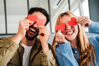 Joyful Couple Holding Heart Shapes to Express Love and Affection on Valentine Day with Bright Smiles and Playful Spirit in a Fun and Engaging Moment Celebrating Their Relationship. High quality photo clipart