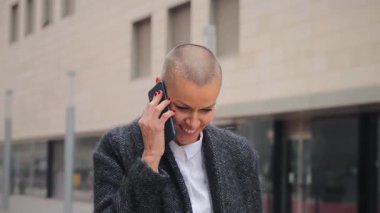 Profesyonellik ve karizma sergileyen, canlı bir telefon görüşmesine katılan kendinden emin bir kadın. Aktif olarak Smartphone ile konuşuyor, Güçlü İletişim Yetenekleri ve Dinamik Kişiliğini somutlaştırıyor