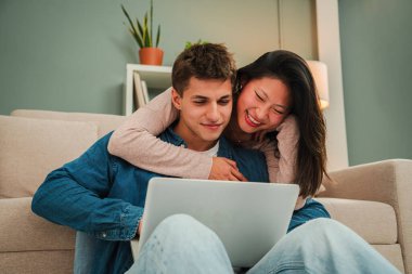 Mutlu çift kanepede dizüstü bilgisayar kullanırken birlikte vakit geçirmenin keyfini çıkarıyor, kahkaha ve mutluluğu samimi bir şekilde paylaşıyorlar, aşkı ve birlikteliği yakalamak için mükemmel. Yüksek kalite