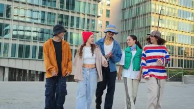 Neşeli bir grup genç arkadaş neşeli bir şehir bölgesinde neşeli bir şekilde yürüyorlar, neşe dolu genç ruhlarla dolu neşeli ve enerjik bir atmosferde gülüşmeler ve iletişim anlarını paylaşıyorlar.