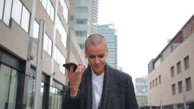 Kendine güveni tam bir iş kadını, canlı bir sesle iletişim kurarken, hareketli bir şehir manzarasında akıllı telefonunu kullanırken, etkili bir şekilde iletişim kurarken yüzünde ışıl ışıl bir gülümseme ve odaklanmış bir ifadeyle. Yüksek