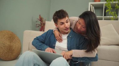Neşeli çift, keyifli bir anda dizüstü bilgisayarda heyecan verici içerikler ararken, keyifli ve samimi bir atmosferde eğlenirken kahkaha ve mutluluklarını paylaşıyorlar.