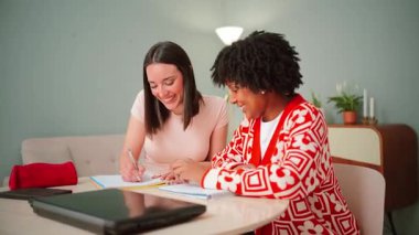 İki odaklı genç kadın, akademik çalışmada takım çalışması ve arkadaşlığın önemini vurgulayarak, öğretim oturumunda fikir ve notlarını paylaşırken, görevler üzerinde sevinçle iş birliği yapıyorlar.