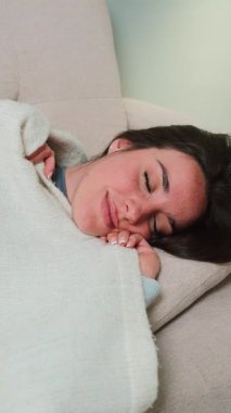 Huzurlu ve huzurlu genç bir kadın, huzurlu bir kanepede uyur, rüyalarında teselli bulur, rahatlamasını kucaklar, dinginliğini ve gençliğini yeniden kazanmasını sağlar.