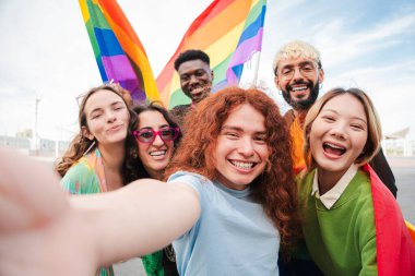 Gurur şenlikleri sırasında renkli gökkuşağı bayrakları taşıyan neşeli bir grup arkadaş, lgbt 'a destek ve mutluluklarını anmak için eğlenceli bir selfie çekiyorlar.