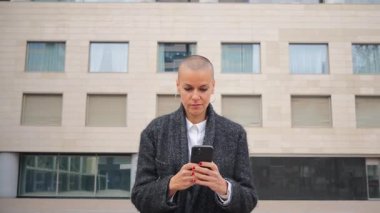 Akıllı telefonuyla etkileşime giren odaklanmış bir bayan, gününü azim ve yetenekle geçirirken işine olan bağlılığını gösteriyor, cep telefonu iletişiminin önemini gösteriyor.