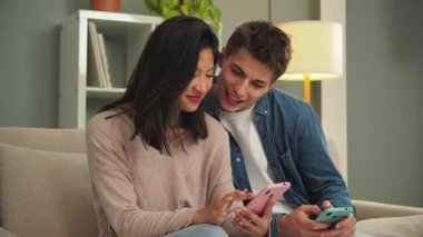 Akıllı telefonlarıyla mutlu bir şekilde etkileşime giren, mobil uygulamalara dalmış ve sıcak ve sıcak bir yaşam alanında birbirlerine eşlik ederek keyifli deneyimler paylaşan bir çift.