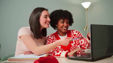 İki neşeli genç kadın, akademik projelerini tartışırken fikirlerini ve sezgilerini paylaşarak bir dizüstü bilgisayarda birlikte çalışmaktan mutluluk duyuyorlar. İşbirlikleri takım çalışmasının özünü gözler önüne seriyor.