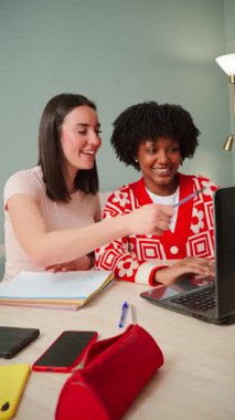 İki neşeli genç kadın, akademik projelerini tartışırken fikirlerini ve sezgilerini paylaşarak bir dizüstü bilgisayarda birlikte çalışmaktan mutluluk duyuyorlar. İşbirlikleri takım çalışmasının özünü gözler önüne seriyor.