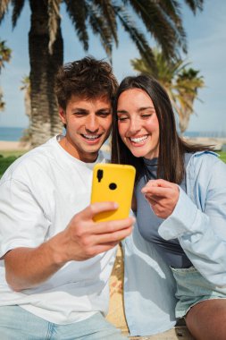 Mutlu çift cep telefonlarındaki bir uygulamayı araştırıyor, güneşli bir açık havada gülüşlerini ve gülüşmelerini paylaşıyor, keyifle dolu unutulmaz bir deneyim yaratıyorlar..