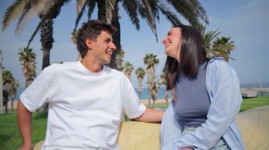 Neşeli bir çift, güzel bir açık hava ortamında birlikte otururken, samimi bir sohbete dalarken, gülücükler ve kahkahalar atarak, bir bağ ve yakınlık anı yaratıyor..