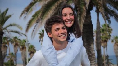 Neşeli bir çift, keyifli bir anın tadını çıkarırken kadın, keyifli etkileşimlerinde mutluluk ve şefkat saçan partnerini sırtında gezintiye çıkarıyor..