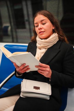 Meşgul bir kadın, toplu taşıma araçlarında seyahat ederken ilgi çekici bir kitabın sayfalarına daldı. Yolculuk sırasında okuma sevincini ve edebiyat ile günlük hayattaki bağlantısını gözler önüne serdi..