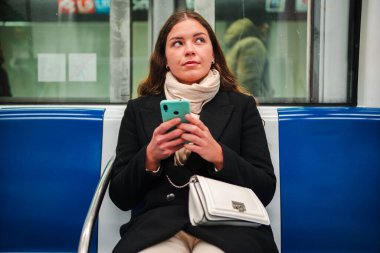 Her gün gidip gelirken metroda otururken akıllı telefonunu kullanarak interneti gezen odaklanmış bir kadın yolcu bir anlık bağlantı ve teknolojiyi yansıtıyor.