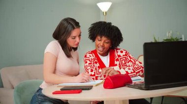 İki odaklanmış öğrenci, bir masada birlikte notlar yazarak, takım çalışmasının önemini ve eğitimde etkili çalışma tekniklerini gözler önüne sererek, bilgi paylaşıyor ve akademik çalışmalar üzerinde işbirliği yapıyorlar.