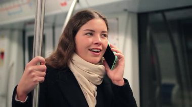 Akıllı telefonuyla konuşan neşeli bir kadın bir metro treninde direğe tutunurken hareketli bir tavır sergiliyor ve her gün gidip gelirken önemli bir sohbete girişiyor.