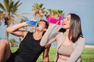 Renkli şişelerle su içen tutkulu bir çift. Mola verip spor salonlarının keyfini çıkarıyorlar..