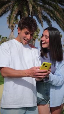 Dikey. Neşeli çift akıllı telefonlarını karıştırıyor, gülüşlerini ve keyifli anlarını paylaşıyorlar..