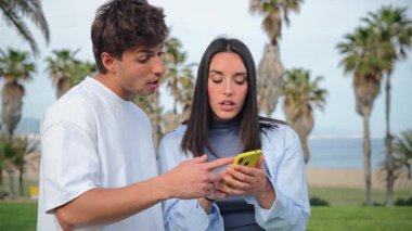 Mutlu çift, açık havada akıllı telefon uygulamasına göz atarken canlı bir etkileşime girmiş.