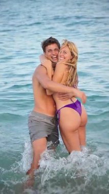 Sıcak okyanus dalgalarında sevgi dolu bir anı paylaşan mutlu bir çift, berrak mavi gökyüzünün altında aşk ve kahkahalarla dolu güzel bir plaj tatilinde birlikte anılar yaratıyor..