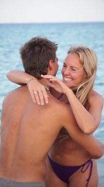 Neşeli bir çift, sakin bir sahilde sevgi dolu bir kucaklaşmayı paylaşıyor güneşli bir tatil boyunca birlikte vakit geçiriyorlar, deniz kıyısında güzel bir yerde mutluluk ve sıcaklık yayıyorlar..